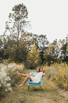 a woman sitting in a blue chair with her legs crossed and feet up on the ground