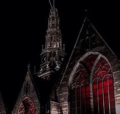 an old church with red stained glass windows and a clock tower in the background at night