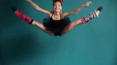 a woman in black top and red shorts doing a split dance