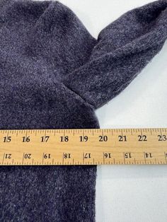 a measuring tape is on top of a gray sweater that has been made into a dress