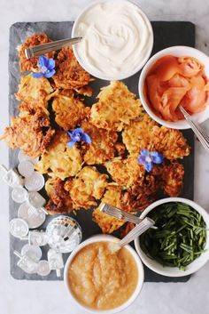 fried chicken with dipping sauces and vegetables on a slate board next to small bowls