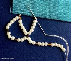 the beads are being sewn together to make a bead necklace with white pearls