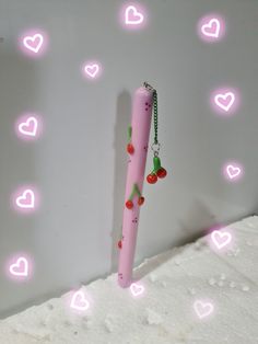 a pink pen with cherries hanging from it's end on a white surface