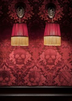 two lamps that are next to each other in front of a wall with skulls on it