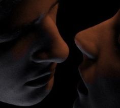 two people are facing each other with their noses close to one another in the dark