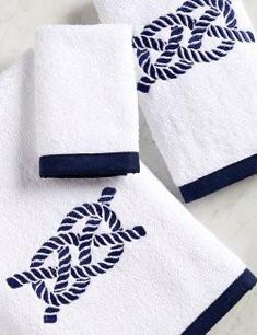 three white towels with blue trim on them sitting on a marble counter top next to each other