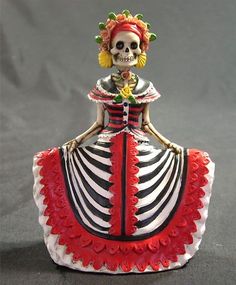 a skeleton figurine in a red and white dress with flowers on her head