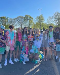 a group of young people standing next to each other in front of a parked car