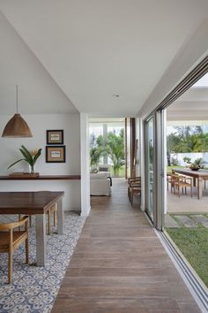 a long hallway leading to an open living room and dining area with sliding glass doors