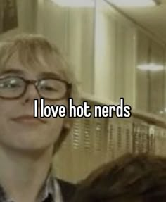 a woman with glasses standing in front of a mirror that says i love hot nerds