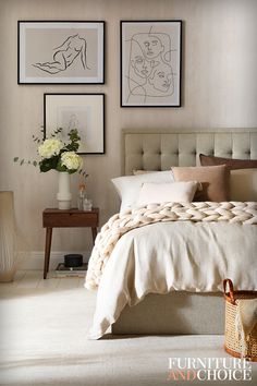 a bedroom with pictures on the wall above the bed and below the bed is a basket full of flowers