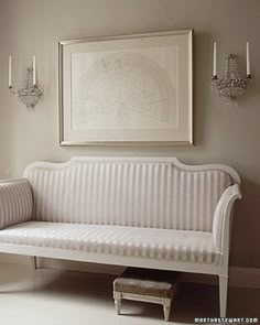 a white couch sitting in front of a window next to a painting on the wall