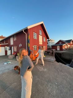 two women standing on top of a dock next to a red building