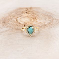 a gold ring with a turquoise stone in the center on a tree stump, close up