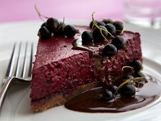 a piece of cheesecake with chocolate sauce and cherries on top, sitting on a plate