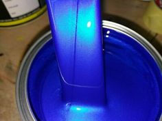 a blue toothbrush sticking out of the top of a can with some paint on it