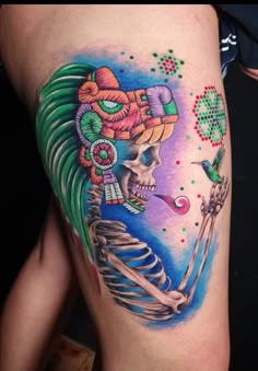 a woman's thigh with a colorful tattoo design on it and a skeleton holding a pipe