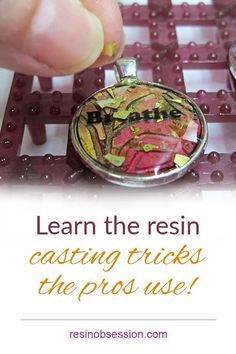 a hand holding a small pendant with words on it that read learn the resin casting tricks the pros use