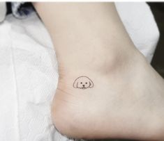 a small dog tattoo on the ankle is shown in black and white, with an outline of a dog's head