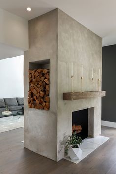 a living room with a fire place and wood stacked on top of each other in front of a couch