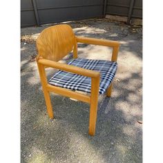 a wooden chair sitting on top of a gravel ground next to a garage door with a checkered seat cover