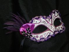 The mask is beautifully decorated in a purple and magenta glitter pattern on a white base colour.  Mask is trimmed in a purple sequin trim, dotted with gems and is attached to ribbons for ease and comfort in hands free wearing.  Features purple coque tip feathers topped off with an asymmetric satin bow and a silver backed rhinestone and silver brooch as the centerpiece. Contact me for a custom order, they are my specialty! Want to see other masquerade masks? Click Here http://www.etsy.com/shop/thecraftychemist07?section_id=7175692 Please take note that if you are outside the US please contact me and I will add the option with the price for the shipping to your country. Pink And Purple Super Hero Accessories Heart Mask, Maskerade Mask Purple, Purple Masquerade Mask, Venetian Masquerade Ball, Masquerade Mask Diy, Ball Masks, Masquerade Ball Masks, Venetian Masquerade Masks, Butterfly Mask