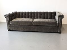 a gray couch sitting on top of a floor next to a white wall in an empty room