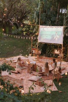 a group of people sitting on top of a blanket in the middle of a yard