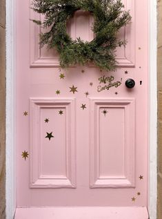 a pink door decorated with gold stars and a wreath