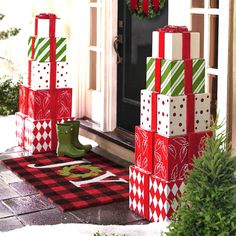 christmas presents are stacked on top of each other in front of a door with wreaths