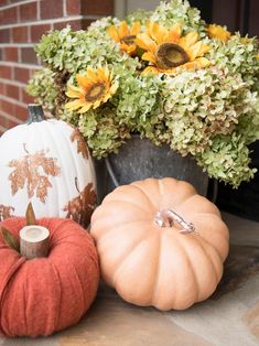 pumpkins and sunflowers are sitting on the front porch for fall decorating