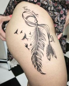 a woman's thigh with a feather tattoo on the leg and an arrow in the middle