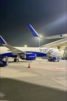 an airplane is parked on the tarmac at night with other planes in the background