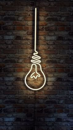 a neon light bulb hanging from the side of a brick wall