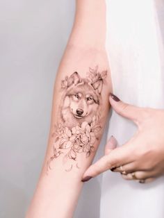 a woman's arm with a wolf and flowers tattoo on the left side of her arm