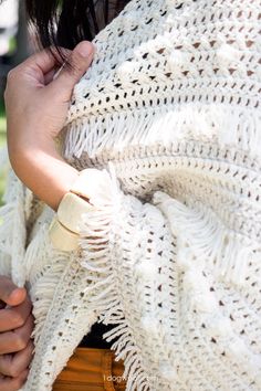 a woman wearing a white crocheted shawl with her hands on her hip