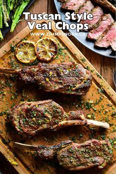 steak chops on a cutting board with lemon wedges and asparagus