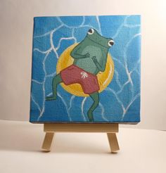 a painting of a frog sitting on top of a wooden easel