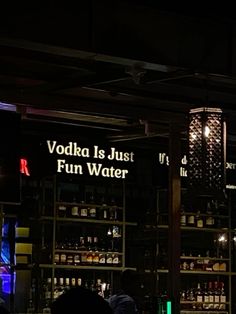 people sitting at tables in front of a bar with neon signs on the wall behind them