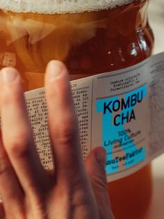 a person holding up a jar of kombu cha