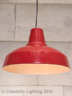 a red light hanging from the ceiling in front of a white brick wall and floor