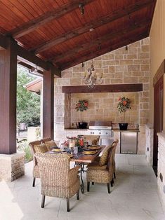 an outdoor dining area with wicker chairs and a grill on the back wall is shown