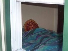 a pizza sitting on top of a bed under a window