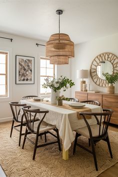 the dining room table is set with four chairs and two vases on top of it