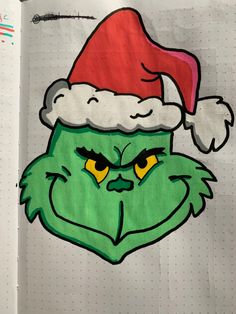 a drawing of the grin face wearing a santa hat on top of a piece of paper