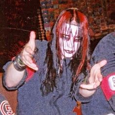 a man with red hair and makeup giving the thumbs up