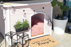 a dog house with plants in it and a welcome mat