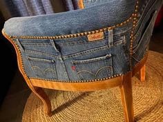 an old pair of jeans sitting on top of a wooden chair with studded legs