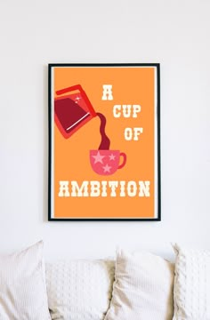 a cup of ambition poster hangs on the wall above a couch with pillows