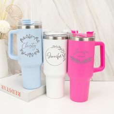 three travel mugs sitting next to each other on top of a white countertop